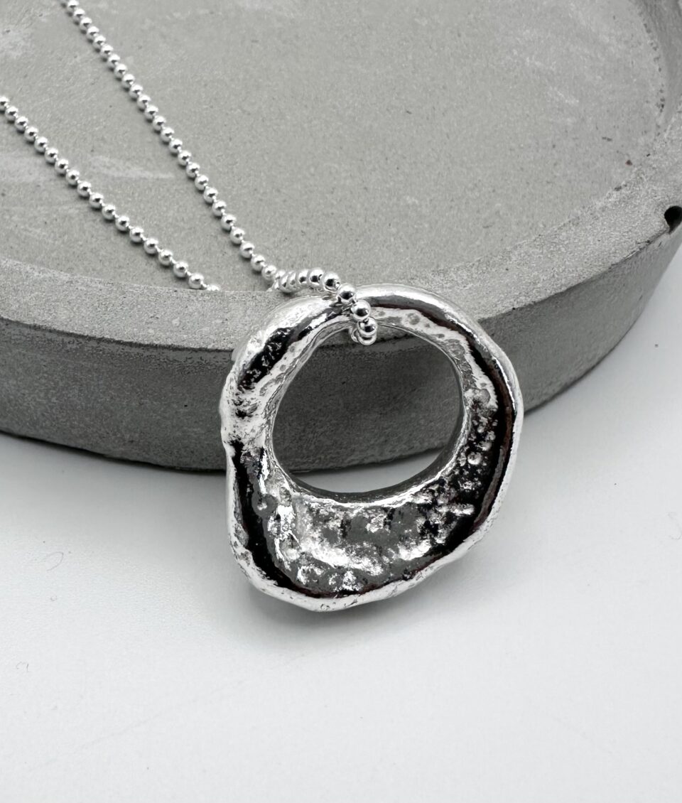Hand molten silver organic pendant necklace on silver ball chain, textured and hallmarked artisan jewellery.