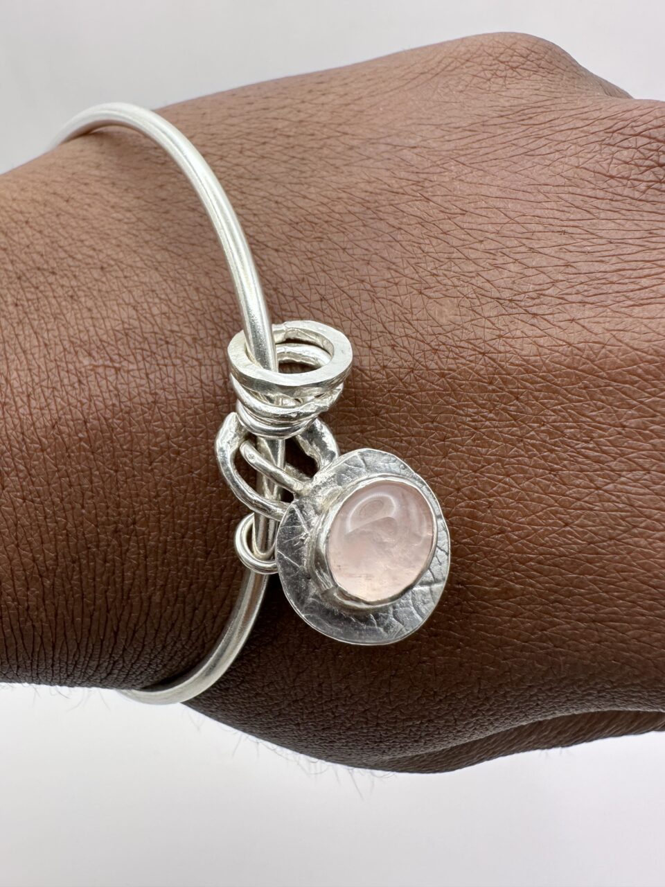 Handmade sterling silver bangle with rose quartz charm on wrist – artisan jewellery by Bohdee.