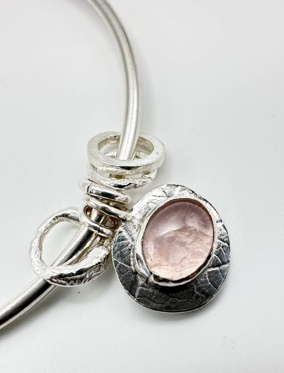 Handmade sterling silver bangle with rose quartz charm on wrist – artisan jewellery by Bohdee.