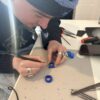 Person carving ring from wav using small hand tools during a jewellery workshop
