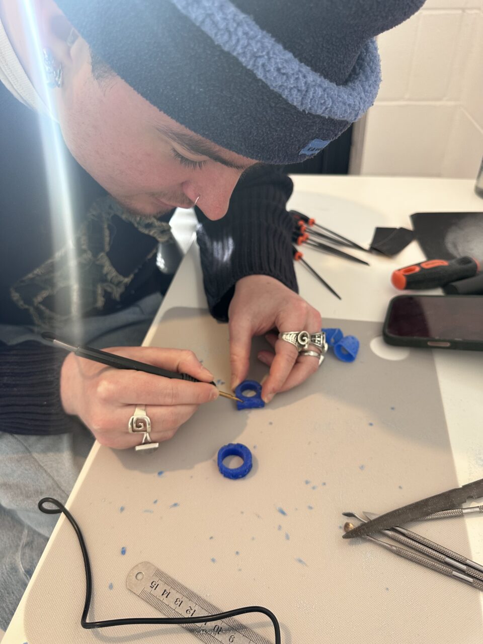 Person carving ring from wav using small hand tools during a jewellery workshop