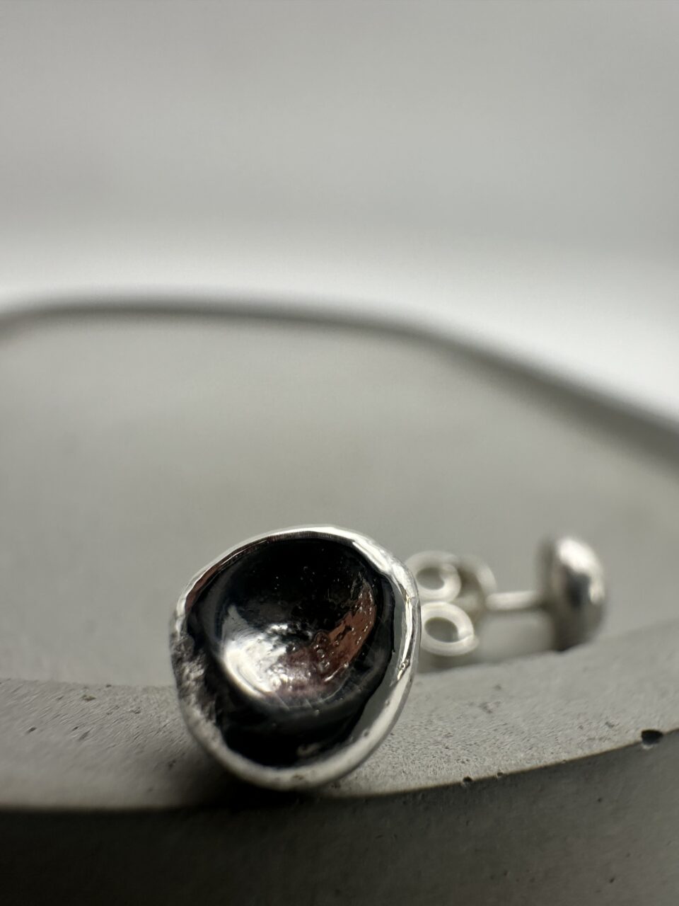 Bohdee tiny solid silver dimple stud earring with a textured recessed centre and polished rounded edge.
