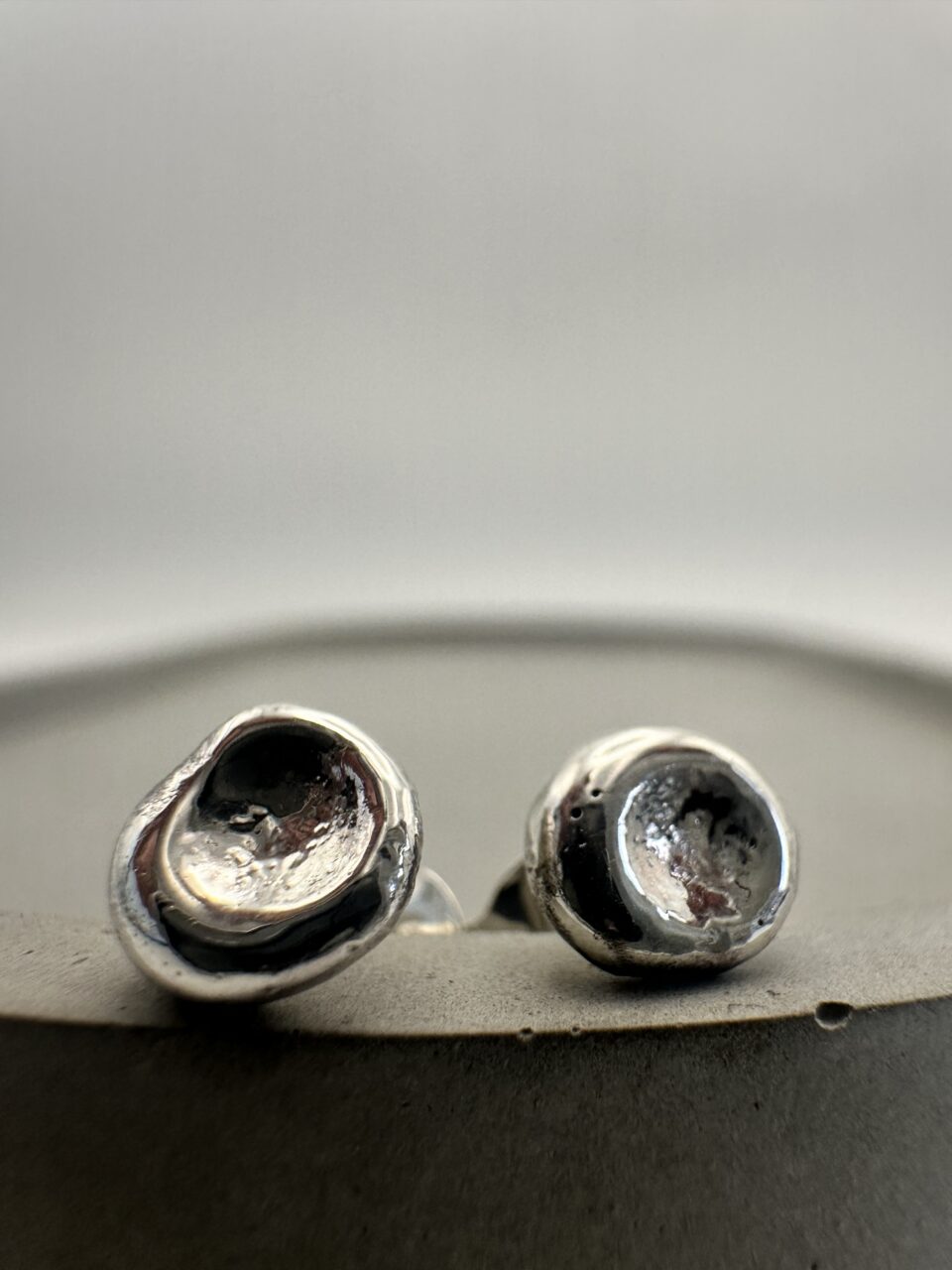 Bohdee tiny solid silver dimple stud earring with a textured recessed centre and polished rounded edge.