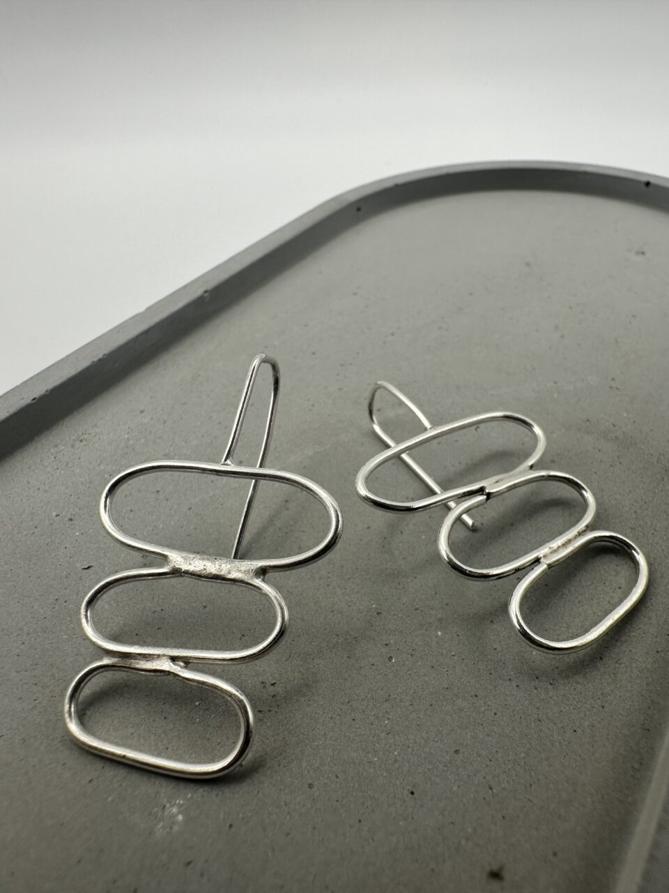 Bohdee recycled silver drop earrings with three stacked open oval shapes and long hook fittings.
